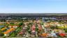 Aerial perspective of a multi-story residence featuring a tile roof, paved driveway, and perimeter fencing within a suburban development
