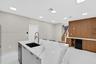 Kitchen island with stone-finish waterfall countertop and undermount sink, recessed lighting, wood-finish wall paneling, built-in cabinetry, and tile 