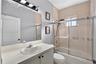 Bathroom featuring a vanity with a white countertop and oval basin, wall-mounted vanity lighting, a full-width mirror, and a tub-shower combination wi