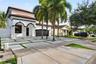 Two-story stucco exterior featuring arched entryways, a tiled roof, multi-car garage, and a concrete paver driveway with integrated green space