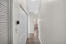 Hallway featuring wood-finish flooring, white louvered closet doors, and a double-panel interior closet door