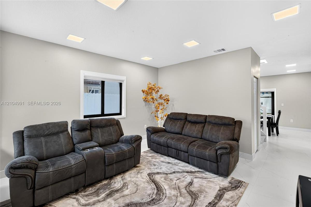 Neutral wall color, recessed ceiling lighting, and large-format tile flooring