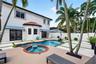 Exterior rear featuring a stucco facade, swimming pool with an attached spa, paver patio with turf inlays, and striped retractable awnings