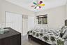 Neutral-toned walls, wood-finish flooring, dual bi-fold closet doors, and a multi-colored ceiling fan with integrated light fixture
