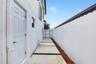 Side exterior featuring a stucco facade, concrete paver path with grass inlay, mulched landscape border, solid perimeter wall, and gated entry