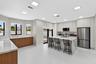 Modern kitchen featuring flat-panel cabinetry, stone-finish countertops with waterfall edge, stainless steel appliances, and large-format tile floorin