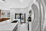 Kitchen featuring a central island with a stone-finish countertop and undermount sink, stainless steel appliances, flat-panel cabinetry, and black-fra