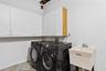Wall-mounted white storage cabinetry, utility sink with chrome faucet, and dedicated laundry hookups
