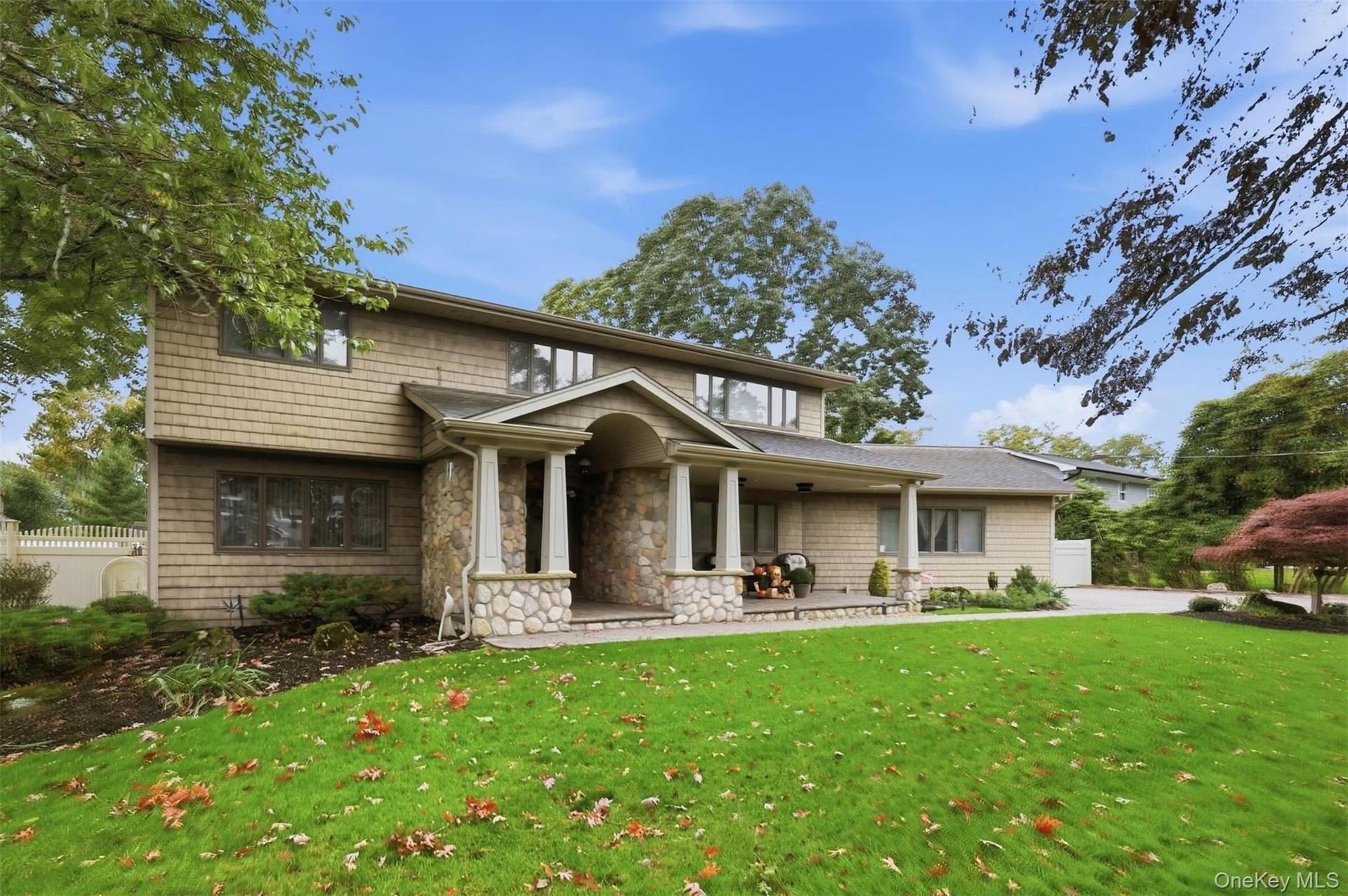 Exterior facade featuring stone veneer detailing, shingle-style siding, a covered entryway with column supports, and a paved walkway