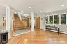 Open-concept interior featuring wood-finish flooring, a central staircase with a wood-finish handrail, architectural columns, multiple wood-finish int