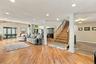 Open-concept interior featuring wood-finish flooring, recessed lighting, decorative white columns, and a wooden staircase with a matching handrail