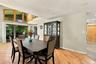 Open-concept dining area featuring wood-finish flooring, vaulted ceilings, expansive multi-pane windows, recessed lighting, and sliding glass doors