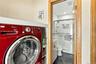 Laundry area featuring a built-in shelf and cabinetry, paired with a bathroom containing a walk-in shower with glass enclosure, tile surround, and dar