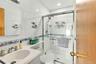 Full bathroom featuring a white vanity with an integrated sink, polished metal fixtures, a shower enclosure with sliding glass doors, and a handheld s