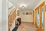 Entry foyer featuring a wood-finish staircase with a decorative railing, double-door entrance with geometric glass panels, wood-finish flooring, and a