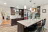Kitchen featuring dark wood cabinetry, quartz countertops, a central island with a stainless steel undermount sink, subway tile backsplash, and built-