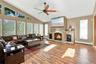 Living room featuring vaulted ceilings, floor-to-ceiling stone-faced fireplace with hearth, wood-finish flooring, multi-pane window configuration, and