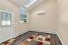 Vaulted ceiling with a skylight, dark wood-finish flooring, energy-efficient mini-split system, and a glass-inset entry door