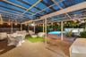 Screened-in outdoor patio with corrugated translucent roofing, brick paver flooring, attached track lighting, and a kidney-shaped swimming pool
