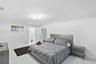 Neutral-toned interior featuring large-format tile flooring and a modern multi-tiered geometric flush-mount light fixture