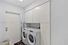 Utility room featuring white, flat-panel built-in cabinetry providing overhead and full-height vertical storage