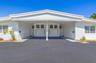 Single-story exterior featuring white stucco siding, a covered central carport, multi-pane windows, and glass block accents