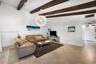 Vaulted ceiling with exposed wood beams, tile flooring, and a spherical statement pendant light fixture