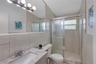 Bathroom featuring a stone-finish countertop, undermount sink, full-width vanity mirror, six-light fixture, and a tiled shower enclosure with sliding 