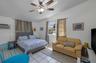 Room featuring white tile flooring, a multi-blade ceiling fan with integrated lighting, and dual windows