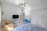 High ceilings featuring a central ceiling fan with integrated light fixture, ceramic tile flooring, and dual white louvered closet doors