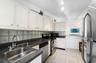 Kitchen featuring white cabinetry, dark stone-composite countertops, stainless steel appliances, a double-basin stainless steel sink, and ceramic tile