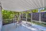 Screened-in porch featuring a corrugated metal roof, aluminum framing, solid flooring, and a private wooden fence perimeter