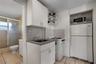 Compact kitchen featuring white cabinetry, hexagonal tile backsplash, stainless steel sink with arch faucet, and light-tone floor tiling