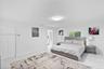 Polished stone-finish flooring, crisp white interior walls, flush-mount ceiling lighting, and a double-door closet with recessed paneling