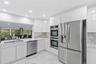 Kitchen featuring flat-panel white cabinetry, stone-surface countertops, stainless steel appliances, double wall ovens, and large-format tile flooring