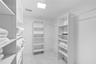 Walk-in closet featuring white built-in shelving, integrated hanging rods, and stone-finish flooring