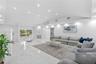 Open-concept living space featuring vaulted ceilings, polished stone-finish flooring, recessed lighting, and a floor-to-ceiling stone-surround firepla