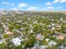 Aerial perspective of a tropical residential community featuring dense canopy trees, manicured lawns, paved street infrastructure, and proximity to an