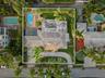 Aerial perspective featuring a tile-roof residence with a curved driveway, a screened-in patio, and an outdoor swimming pool set within a landscaped l