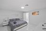 Large-format tile flooring with a neutral-toned veined finish, recessed lighting, and crisp white wall surfaces