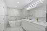Modern bathroom featuring floor-to-ceiling stone-look tiling, a freestanding soaking tub with a wall-recessed niche, a dual-sink floating vanity, inte