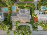Aerial perspective of a property featuring an in-ground swimming pool, a screened-in patio area, a concrete driveway, and mature landscaping