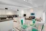 Open-concept interior featuring vaulted ceilings with exposed beams, ceramic tile flooring, a kitchen peninsula, and recessed lighting