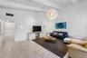 Vaulted ceilings with exposed beams, large spherical chandelier, and ceramic tile flooring