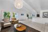 Vaulted ceilings with exposed beams, large-format tile flooring, oversized spherical pendant lighting, track lighting, and a breakfast bar counter