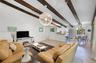Vaulted ceilings featuring exposed wood beams, a contemporary sputnik-style chandelier, track lighting, and tile flooring