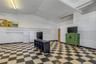 Interior space featuring vaulted ceilings, high-contrast checkerboard flooring, linear wall-mounted shelving, and integrated pegboard wall panels