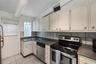 Kitchen featuring white cabinetry, dark stone-finish countertops, stainless steel appliances, a square glass block window, and tile flooring