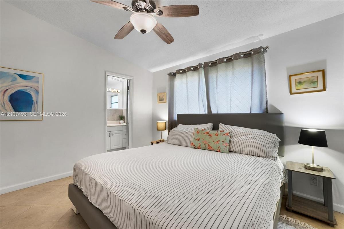 Neutral interior featuring tile flooring, a multi-blade ceiling fan with integrated lighting, and horizontal window treatments