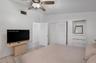 Room featuring vaulted ceilings, neutral ceramic tile flooring, ceiling fan with integrated lighting, built-in wooden shelving, and a closet with louv